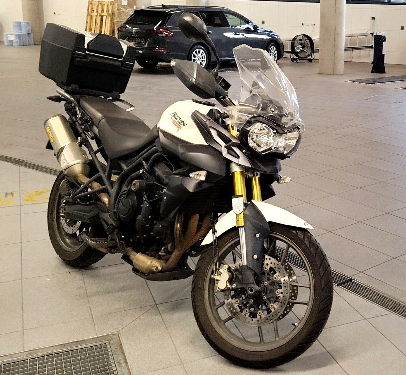 Weiße Triumph Tiger 800 mit Topcase, Drei-Viertel-Frontansicht in heller Halle